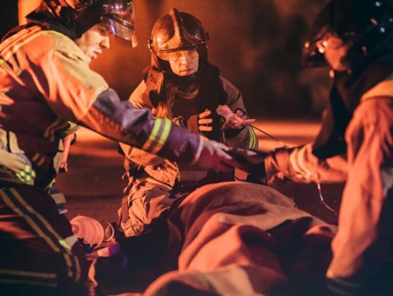 Firefighters rescuing teenagers from a house fire and providing CPR at night