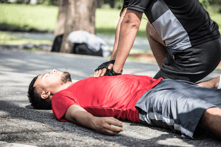 Bystander performing CPR on an unconscious man who collapsed during a jog on a city sidewalk