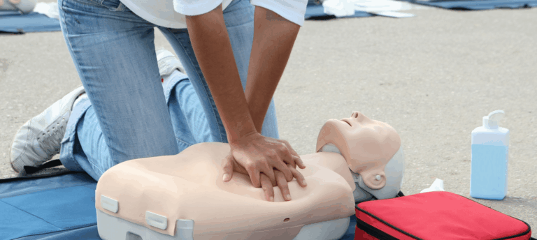 Student performing CPR chest compressions during first aid training, demonstrating proper life-saving technique using a CPR mannequin.