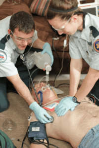 Paramedics providing emergency CPR and oxygen support to an unconscious cardiac arrest patient during a medical emergency.