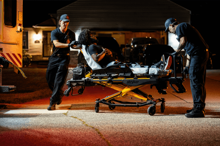 Paramedics transporting an elderly patient on a stretcher after a serious fall at a care facility.