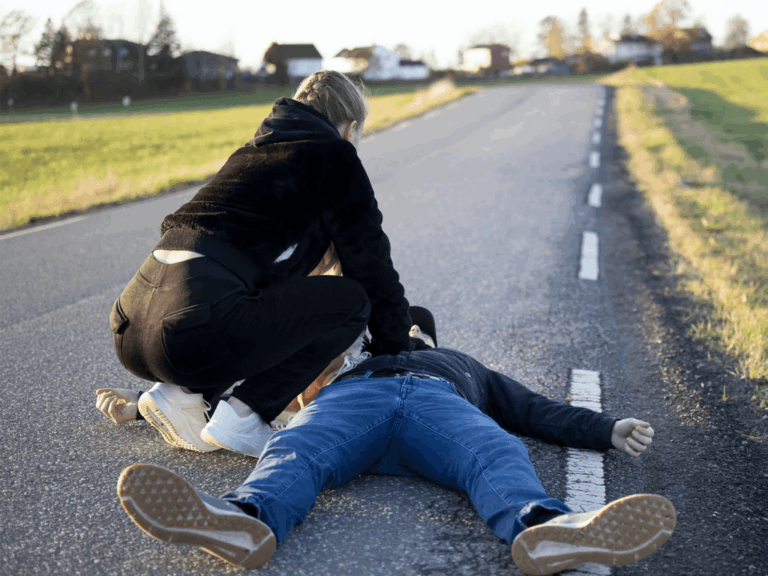 Bystander performing CPR on an unconscious man during a roadside emergency